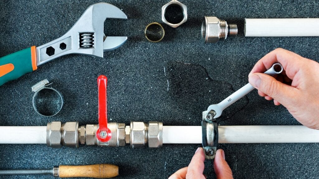 Plumber repairing a pipe valve with an adjustable wrench in Pompano Beach