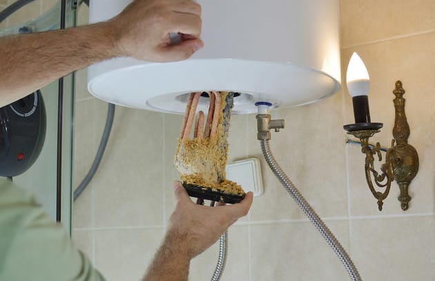 Technician removing mineral buildup from a water heater in Pompano Beach